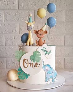 a birthday cake with animals and balloons on the top is decorated in pastel colors