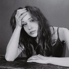 a black and white photo of a woman sitting at a table with her hands on her head