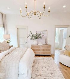 a bedroom with a large bed, two chairs and a chandelier hanging from the ceiling