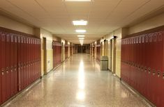 a long hallway with rows of red lockers on the walls and doors to either side