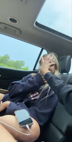 a woman sitting in the back seat of a car talking on her cell phone