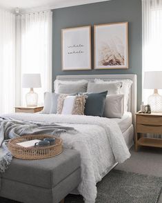 a bedroom with gray walls and white bedding, two framed pictures on the wall