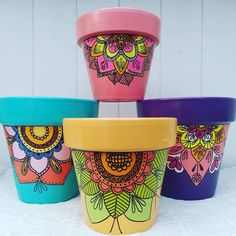 four colorful flower pots sitting next to each other