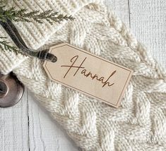 a white sweater with a name tag hanging from it's side next to a bottle opener