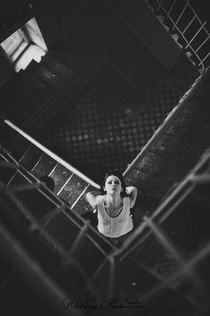 black and white photograph of a woman standing on stairs with her hands behind her head