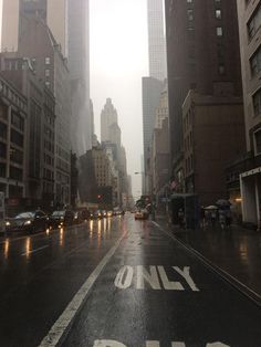 an empty city street in the rain with only one way sign painted on the road