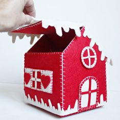 a hand is opening the top of a small red house