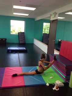 a woman sitting on top of a multi colored mat in an office building with yoga mats