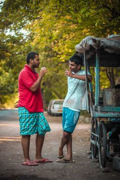 two men standing next to each other in front of a cart