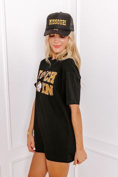 - Football, but make it fabulous with this shimmering tee! Its unique sequined design makes it a perfect addition to any sporty fashionista's game day collection. Stay at the top of the tailgate game with this sporty-chic piece! - Unlined 100% cotton material - A sequined white, black, gold, and brown hued 'TOUCHDOWN' design featuring footballs, a goal post, and a helmet - A crew cut neckline - Short, loose sleeves - A relaxed silhouette that ends in a straight hemline - This piece is perfect fo Black Tops For Baseball Game Day, Trendy Black T-shirt With Glitter Print, Casual Black Tops With Glitter Print, Casual Black Sequined T-shirt, Black T-shirt With Glitter Print And Short Sleeves, Black Short Sleeve T-shirt With Glitter Print, Black T-shirt For Game Day In Fall, Black T-shirt For Fall Game Day, Casual Glitter Print T-shirt For Game Day