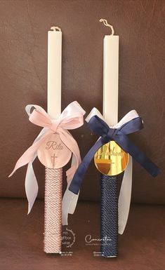 two tall candles with ribbons tied around them, one is blue and the other is pink