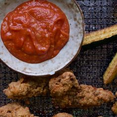 some fried food is sitting on a plate with ketchup and sauce in it