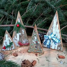 three wooden christmas trees sitting on top of a table next to pine cones and other decorations