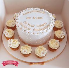 a white cake with frosting and cupcakes on the side in a box