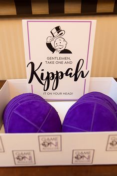 two purple balls sitting in a box with a sign on the top that says, genit eleki take one and kipp it on your head