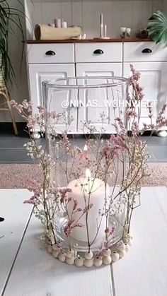 a white candle sitting on top of a table next to a vase filled with flowers