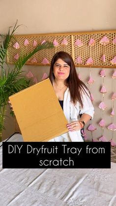 a woman sitting on a bed holding a cardboard box in front of her face with the words diy dry fruit tray from scratch