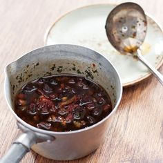 a pot filled with food sitting on top of a wooden table next to a plate