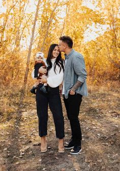 a man and woman are standing in the woods with their baby