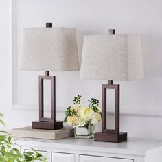 two lamps sitting on top of a table next to a vase with flowers in it