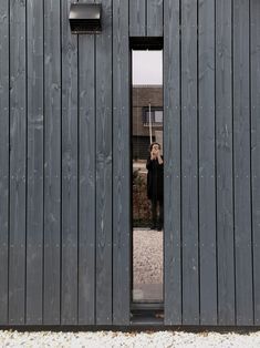 a woman taking a selfie in front of a wooden building with two doors open