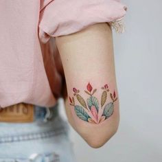 a woman's arm with a tattoo on it that has leaves and flowers painted on it