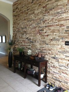 a room with a table, vases and other items on the floor in front of a brick wall