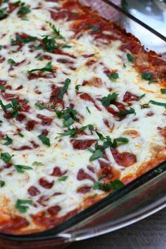 a close up of a pizza in a casserole dish with cheese and toppings