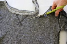 a person cutting fabric with scissors on top of a piece of cloth that has been cut in half