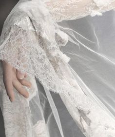 a close up of a person wearing a wedding dress and veil with hands on it