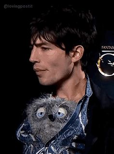 a man holding a stuffed animal in his right hand and looking at the camera with an evil look on his face