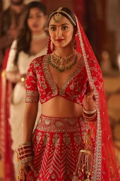 a woman in a red and gold bridal outfit standing next to two other women