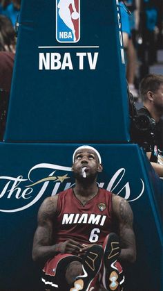 a man sitting on the side of a basketball court