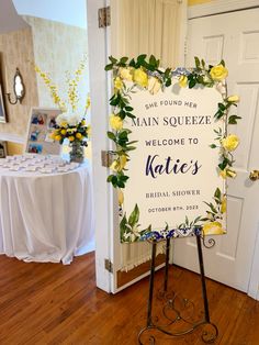 a welcome sign in front of a white door with yellow roses and greenery on it