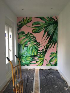 a room that has been painted with pink and green tropical leaves on the wall behind it