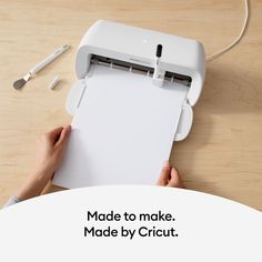 a person holding a piece of paper over a machine with the words made to make made by cricut