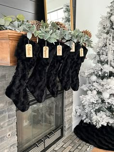 stockings hanging from a fireplace mantle with christmas decorations and greenery in front of it