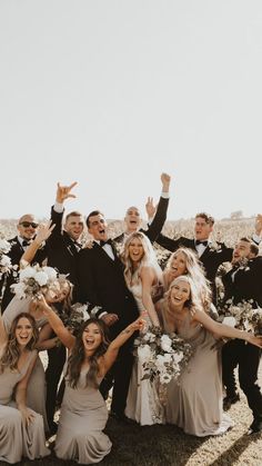 a group of people standing next to each other with their arms in the air and smiling