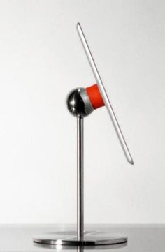 an orange and silver object on a metal stand with a white wall in the background