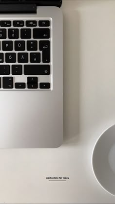 a laptop computer sitting on top of a white desk next to a mouse and coffee cup