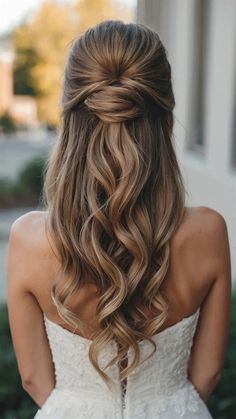 a woman with long hair in a wedding dress looking down at her shoulder and back