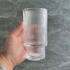 a hand holding up a clear glass cup