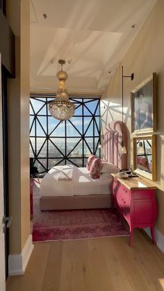 a bedroom with pink furniture and a chandelier hanging from the ceiling above it