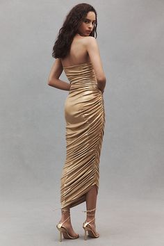 a woman in a gold dress is posing for the camera with her hands on her hips