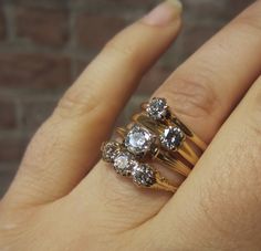 a woman's hand with three different rings on top of her finger and the other ring