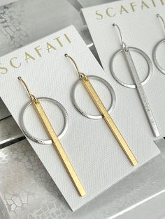 "Very simple textured hoops enhanced with a textured bar. The hoops are rack plated with a silver alloy and 18 K gold over brass. Rack plating means they are hand hung so there is optimal coverage and the plating has a glossy finish. Two finish combinations are available: Silver - 2 1/2\" in length Silver and Gold 2 1/2\" in length The wires are plated with 16 K Gold and a silver alloy over brass and come with rubber back stoppers. All metals are lead safe." Textured Small Hoop Jewelry For Gifts, Textured Small Hoop Jewelry Gift, Textured Metal Hoop Earrings For Gift, Textured Hoop Jewelry For Gifts, Textured Hoop Jewelry Gift, Textured Drop Earrings For Gifts, Modern Hammered Linear Earrings For Gift, Modern Hammered Linear Earrings As Gift, Textured Metal Drop Earrings