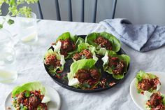 lettuce cups filled with meat and vegetables on a white table cloth next to water glasses