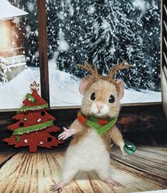 a small mouse standing in front of a window with christmas decorations on the windowsill