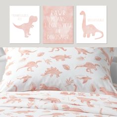 a bed with pink and white dinosaur prints on the wall next to two pillow cases