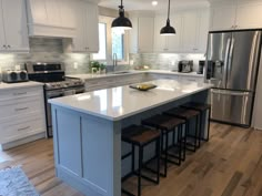 a large kitchen with an island in the middle and four stools at the end